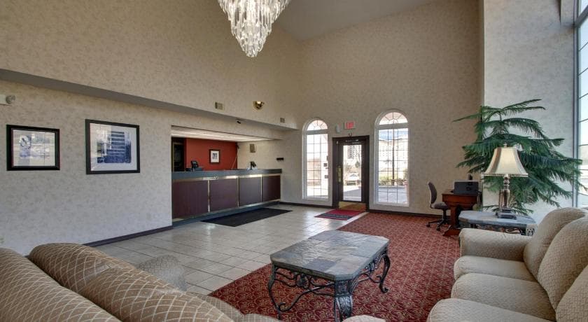 Bright hotel lobby at Angel Inn Central in Branson MO with front desk, seating area, chandelier, and large windows