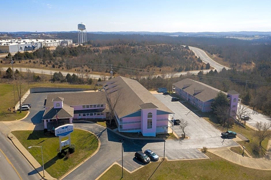Aerial view of the Angel Inn Central hotel exterior and entrance in Branson, MO with parking lot and surrounding hills