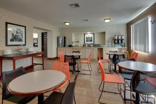 Hotel breakfast area at Angel Inn Central in Branson MO with round tables, colorful chairs, and a breakfast counter