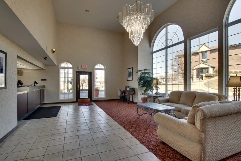 Angel Inn Central hotel lobby in Branson, MO with a chandelier, large arched windows, comfortable seating, and a reception style entry area