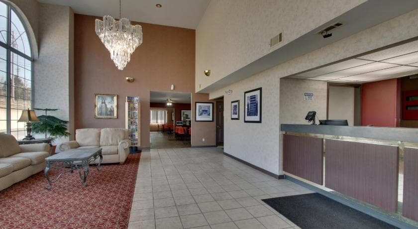 Angel Inn Central hotel lobby in Branson MO with front desk, chandelier, seating area, and large arched window