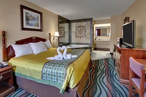 Queen room at Angel Inn Central in Branson MO featuring a queen bed, flat screen TV, vanity area, and patterned carpet