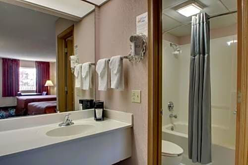 Bathroom vanity and shower area in an Angel Inn Central queen room, with a view into the adjoining bedroom in Branson, Missouri